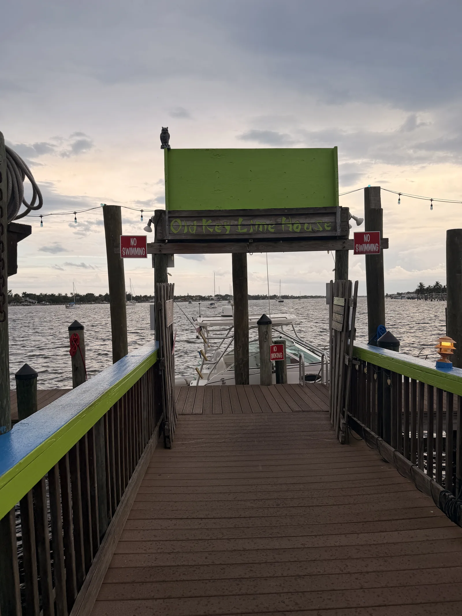 The green-trimmed dock at Old Key Lime House with No Swimming signs, a boat moored alongside