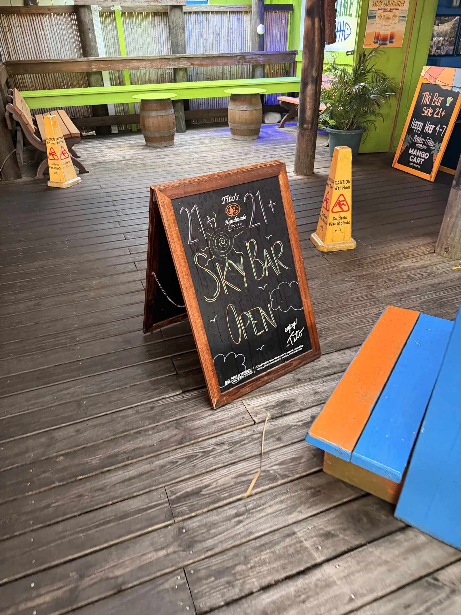A chalkboard at Old Key Lime House reading Sky Bar open, 21 and over, barrels and benches behind