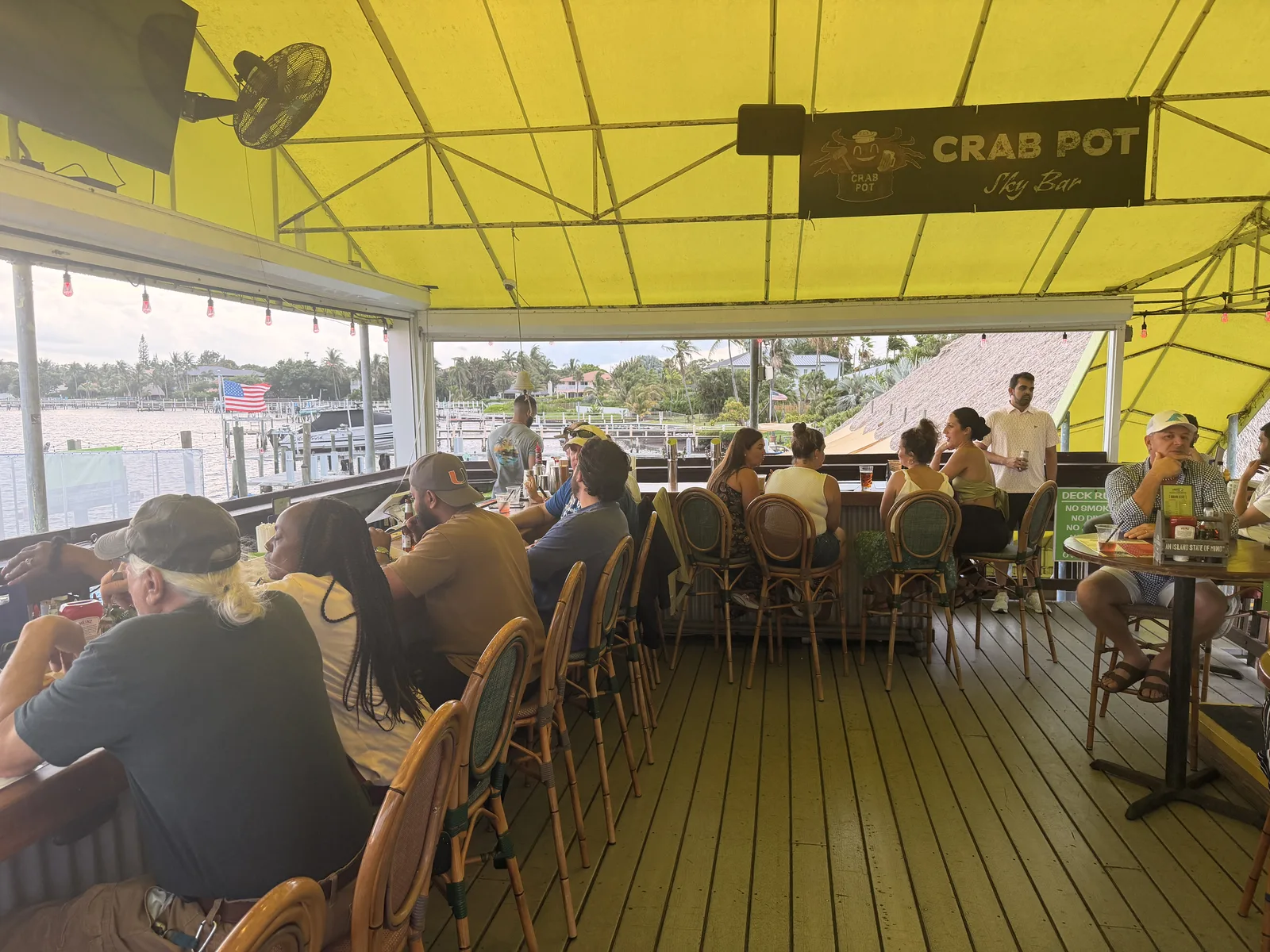 Guests under the yellow canopy at Old Key Lime House, the river and moored boats just beyond