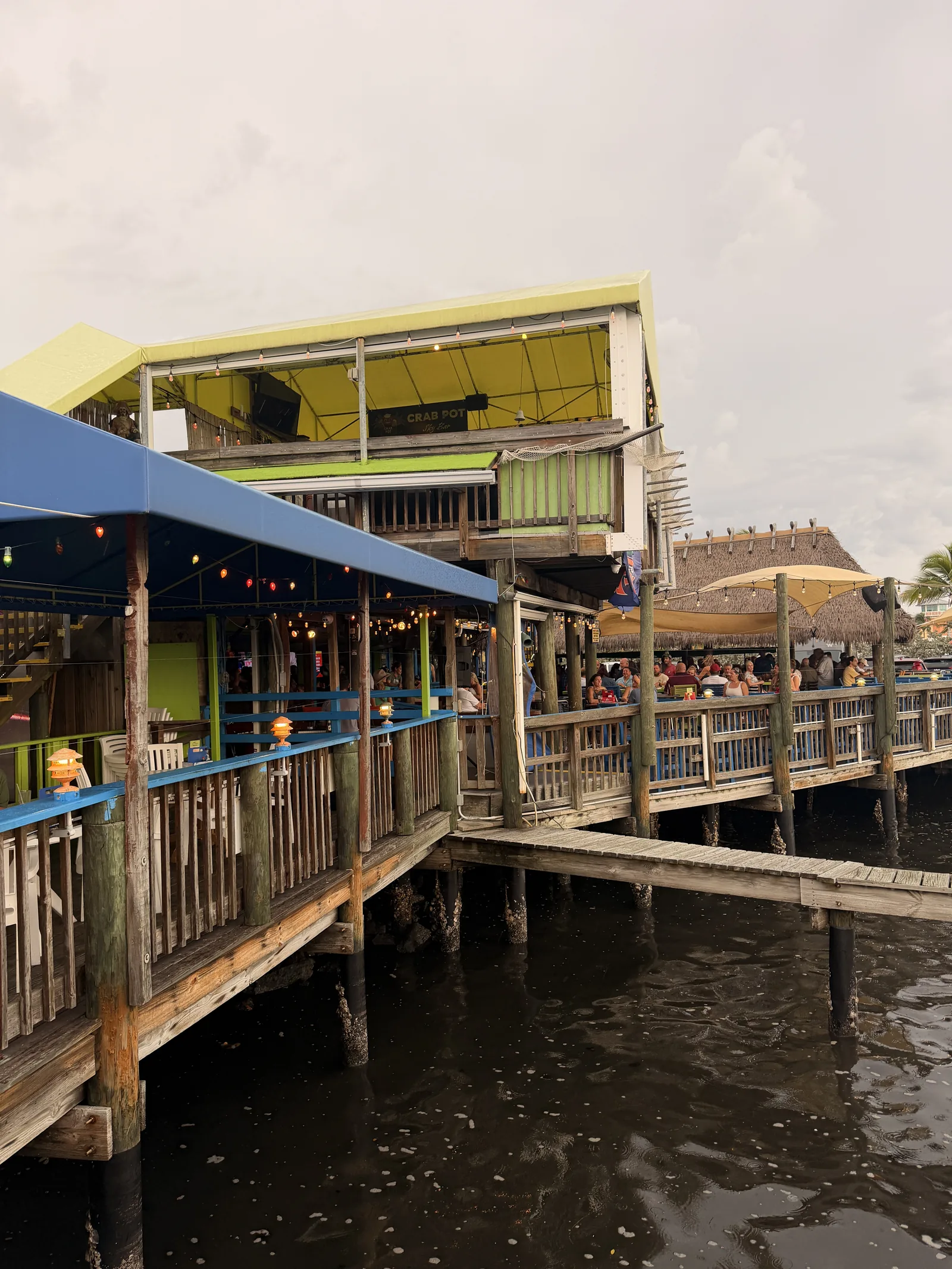 Diners under string lights on the waterfront deck at Old Key Lime House, blue railings over water