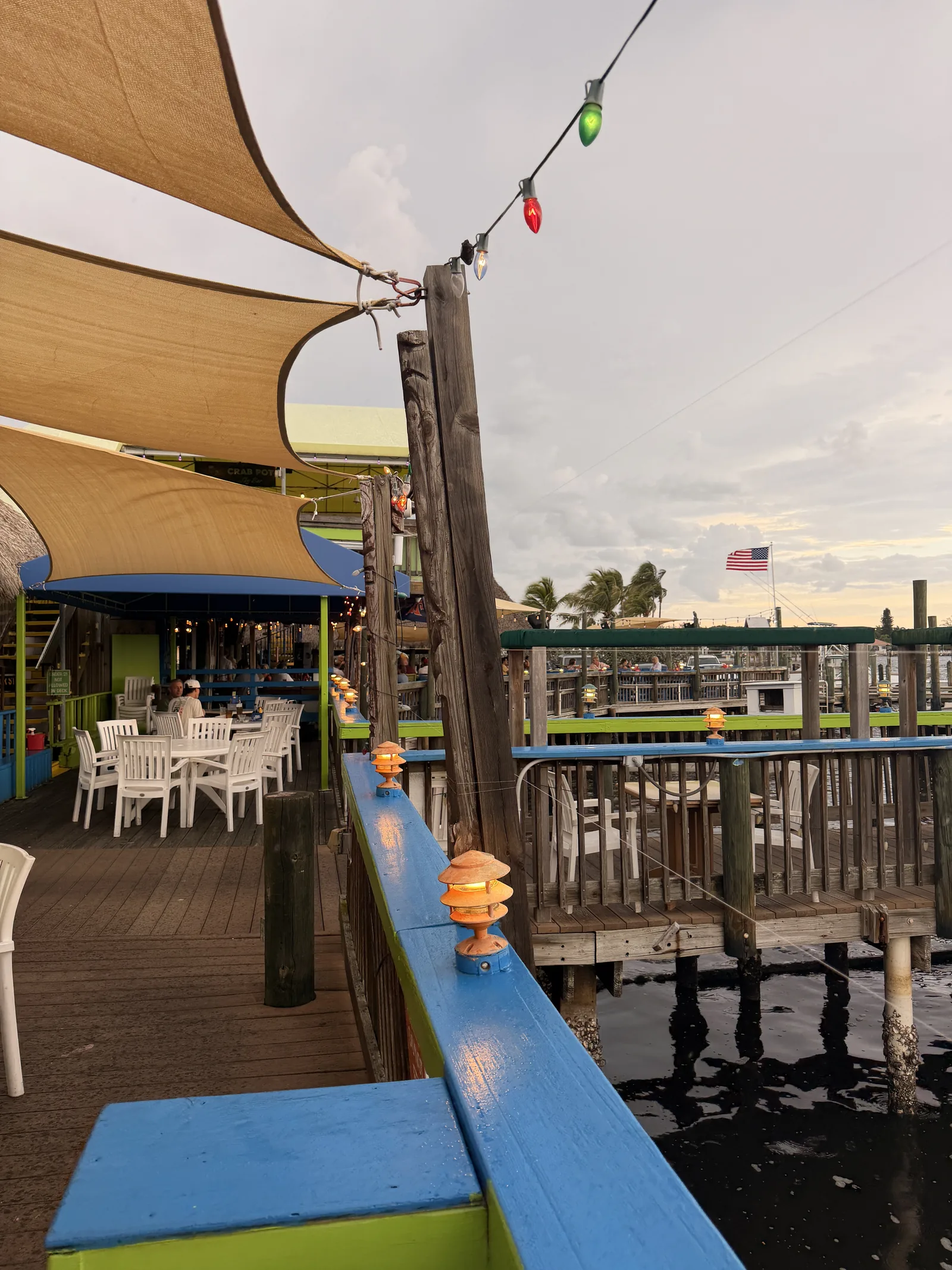 Empty white tables on the dock at Old Key Lime House, colorful lights strung along the railings