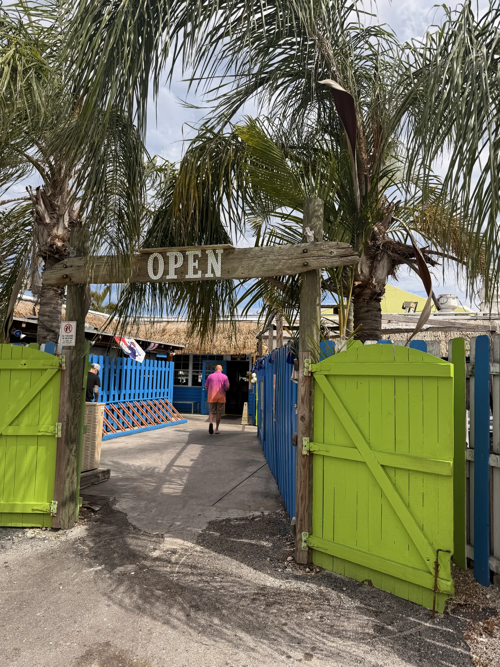 The green gates and wooden Open sign at Old Key Lime House, blue fence along the walkway