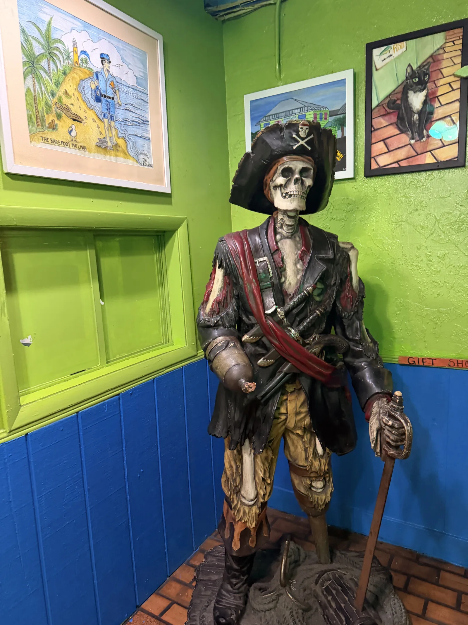 A life-sized pirate skeleton in tattered clothes standing inside Old Key Lime House