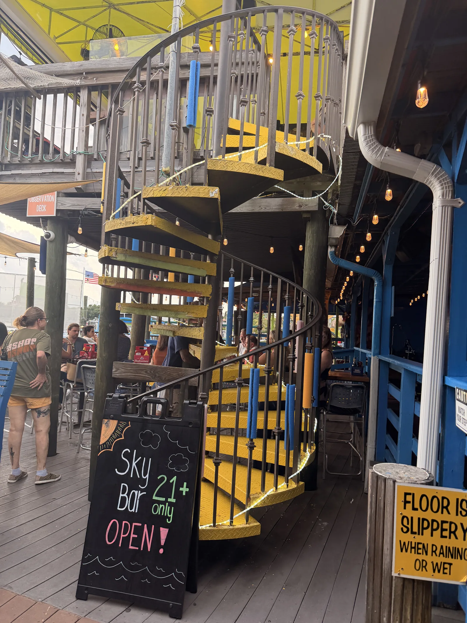 The yellow spiral staircase up to the Sky Bar at Old Key Lime House, guests at tables below