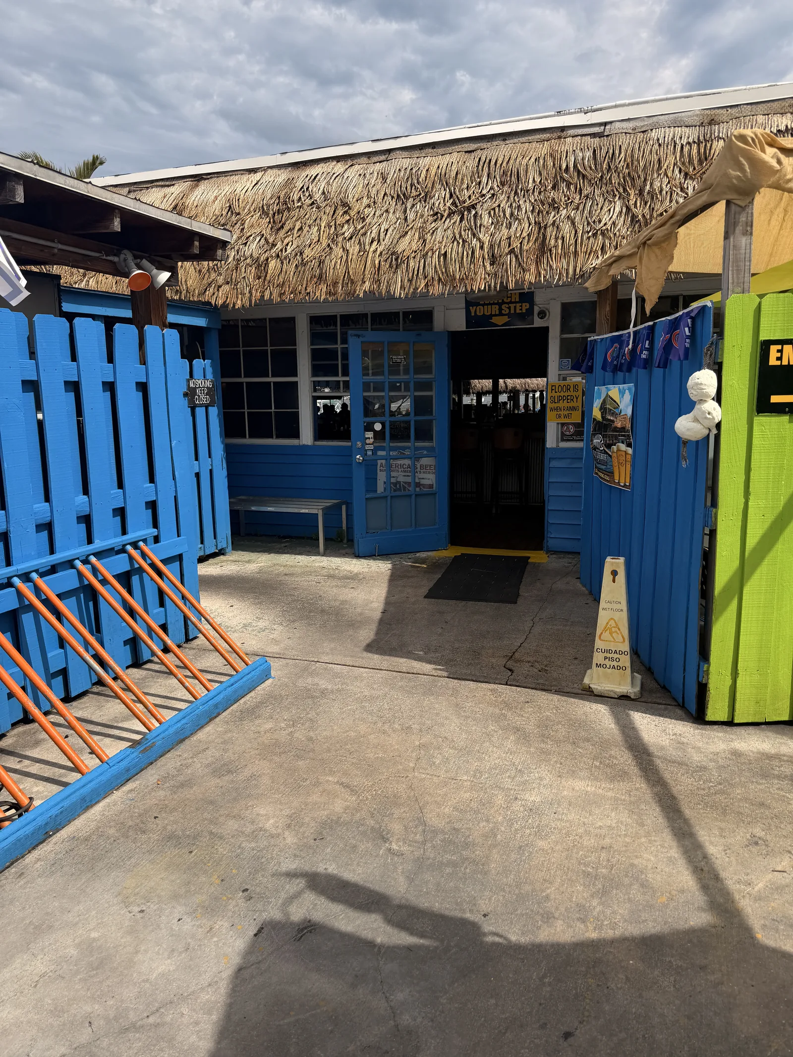 The thatched entrance at Old Key Lime House, blue doors open behind the green gate